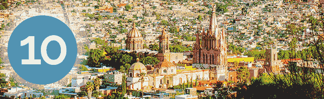A cityscape of San Miguel de Allende, Mexico, featuring colorful colonial buildings and a prominent church, with a large blue circle displaying the number 10 on the left side—perfect for showcasing top resorts or conference events.