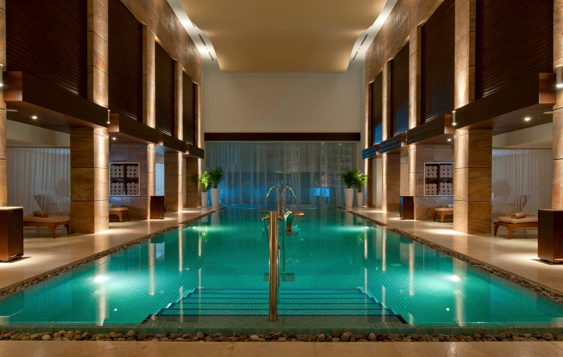 Luxurious indoor swimming pool with turquoise water, surrounded by elegant columns, warm lighting, and lounge chairs—perfect for relaxing after conference events at upscale Mexico resorts and hotels.