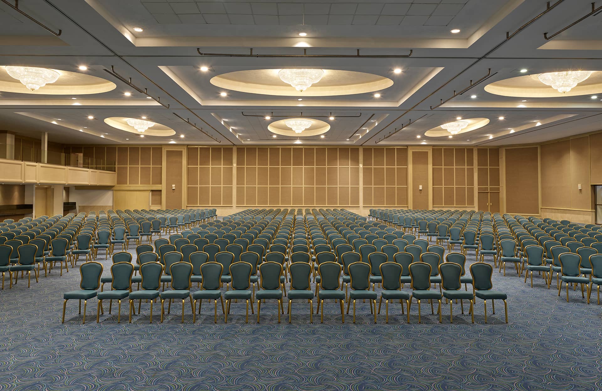 A spacious conference hall at one of Mexico’s top resorts, featuring rows of blue chairs, ornate chandeliers, and patterned blue carpet—ideal for meetings and unforgettable conference events.