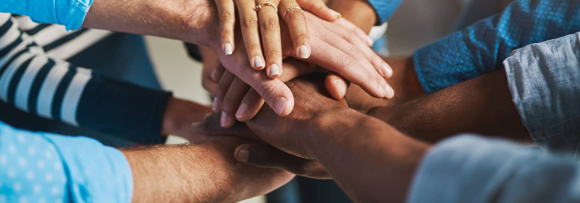 At conference events in Mexico hotels, a group stands in a circle and stacks their hands together, symbolizing teamwork, unity, and inclusivity—qualities celebrated at leading meetings and resorts.