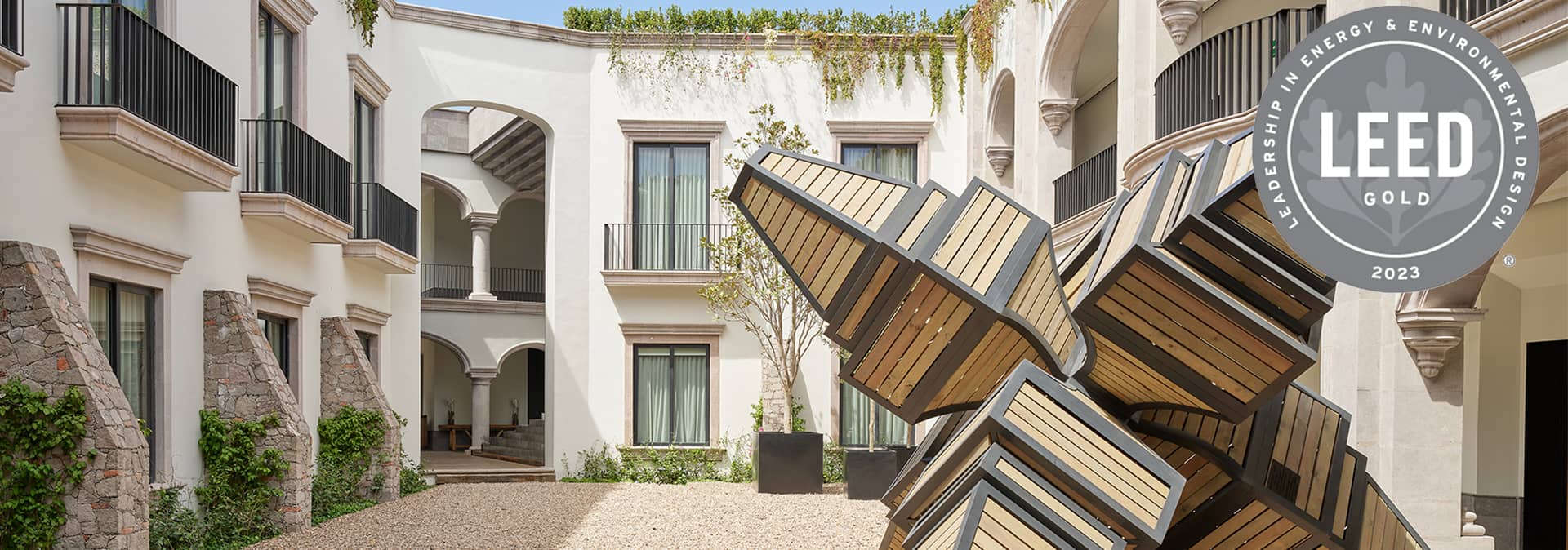 A modern courtyard at one of Mexico's premier hotels, with large windows, arched walkways, and a geometric wooden sculpture. Perfect for meetings or conference events. The LEED Gold 2023 certification badge is displayed in the upper right corner.