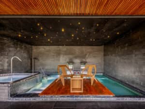 El moderno spa interior de uno de los mejores resorts de México cuenta con una piscina resplandeciente, una terraza de madera, un jacuzzi y un techo estrellado, ideal para relajarse después de eventos o reuniones en hoteles de lujo.