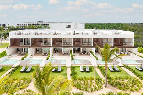 Modern resort building with private patios and plunge pools, surrounded by green lawns, palm trees, and landscaped gardens—an ideal setting for meetings or conference events at top Mexico hotels.