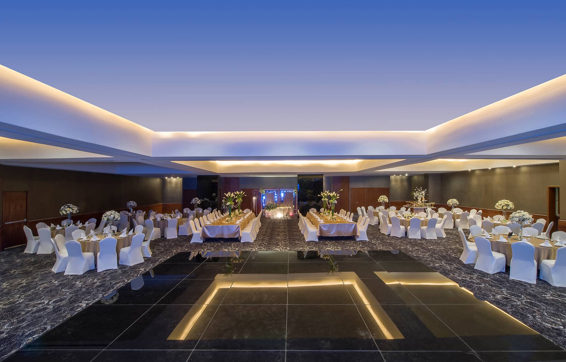 Elegant banquet hall at one of Mexico’s finest resorts, featuring modern lighting, round tables with white cloths, and white chairs along a glossy black-tiled floor—perfect for formal meetings, conference events, or receptions.