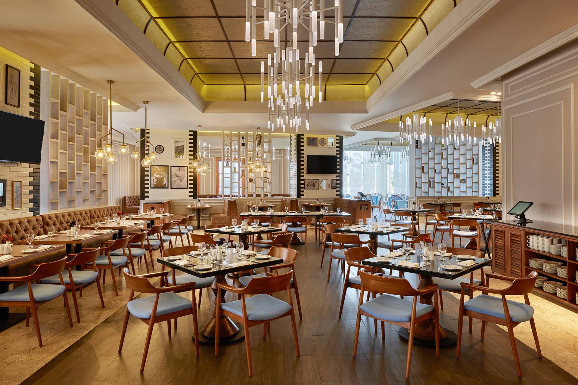 Modern restaurant interior in one of Mexico’s top resorts, featuring wooden tables, elegant chandeliers, and large windows. Perfect for meetings or conference events, the warm lighting and stylish decor create a welcoming atmosphere.