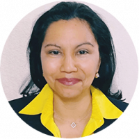 A woman with medium-length dark hair, wearing a black blazer with a bright yellow collar and a light-colored necklace, smiles at the camera against a light background—perfectly dressed for Mexico hotels conference events.